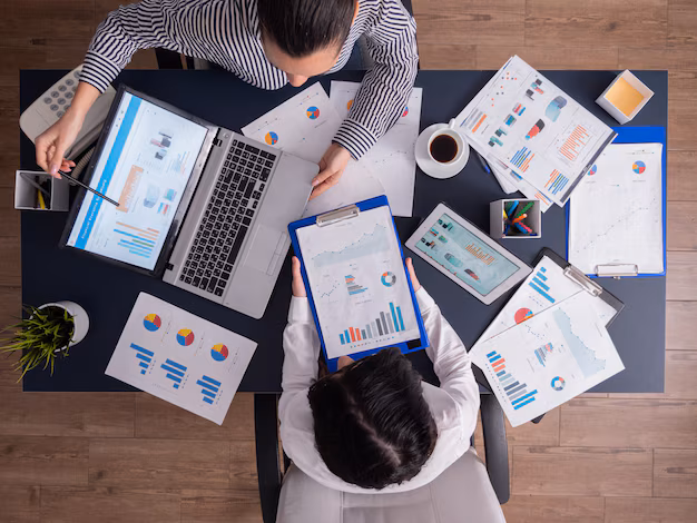 top-viewtop-view-manager-employee-doing-teamwork-business-office-looking-charts-laptop-display_482257-2443